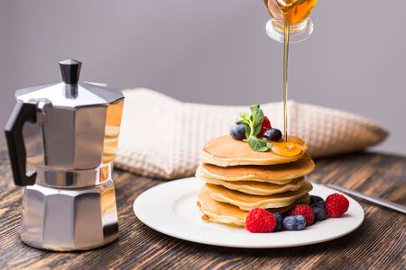 Woman pouring maple syrup on tasty pancakesの写真素材