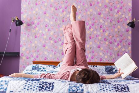 Happy woman wears pajama and relaxing at home and reading a book. Stay home. Quarantine pandemic coronavirus concept.の写真素材