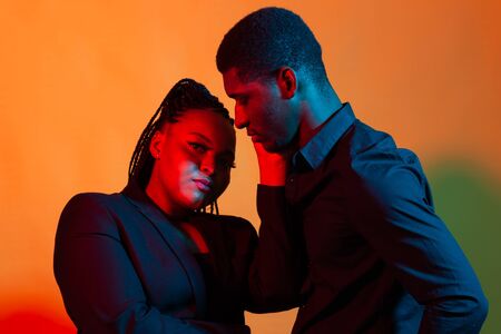 Dark neon portrait of young african american man and woman. Red and blue light.の写真素材