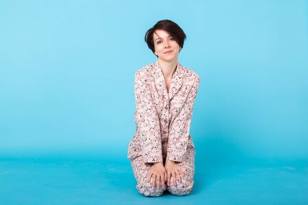 Young girl posing in pajamas on blue background. Relax good mood, lifestyle and sleepwear concept.の写真素材