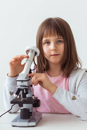 Child girl in science class using digital microscope. Technologies, children and learning concept.の写真素材