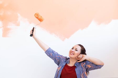 Beautiful woman painting wall in her new apartment. Renovation and redecoration concept.の写真素材