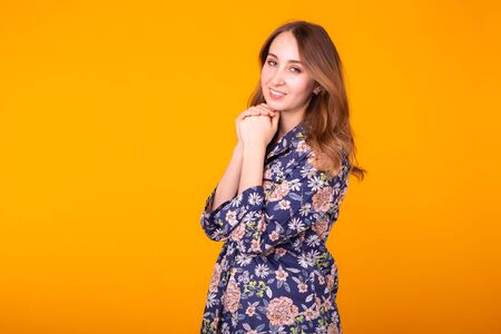 Excited young woman with curly hair in home wear pajama, widely smiling having fun. Isolated on yellow background.の写真素材