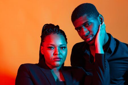 Dark neon portrait of young african american man and woman. Red and blue light.の写真素材
