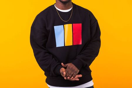 Youth street fashion concept - Close-up of black man in stylish sweatshirt on yellow background.の写真素材
