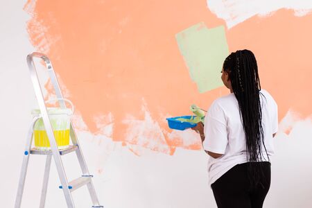 Afro american woman painting an apartment. Renovation, repair and redecoration concept.