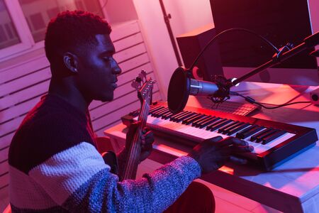 African american professional musician recording synthesizer in digital studio at home, music production technology concept.の写真素材