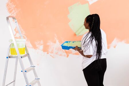 Lovely african american housewife painting wall. Renovation, redecoration and repair concept.の写真素材