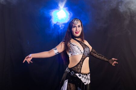 Young woman belly dancer in exotic dress with gold, dancing tribal fusion dance in studio.の写真素材