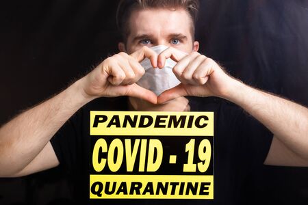 Man in medical mask showing heart gesture. Guy misses his family isolated in hospital. Stop...