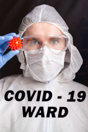 Covid-19, Vaccine development and medicine concept - Man scientist or doctor dressed personal protective equipment and holding a model of coronavirus.の写真素材