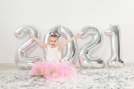New year, holidays and celebration concept - Little child girl sitting near with numbers balloons 2021の写真素材