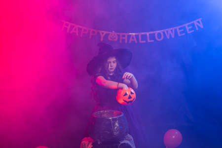 Funny child girl in witch costume for Halloween with pumpkin Jack.