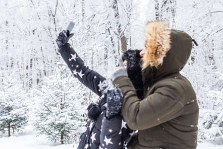 Season and relationship concept - Funny couple taking selfie in the winter timeの写真素材