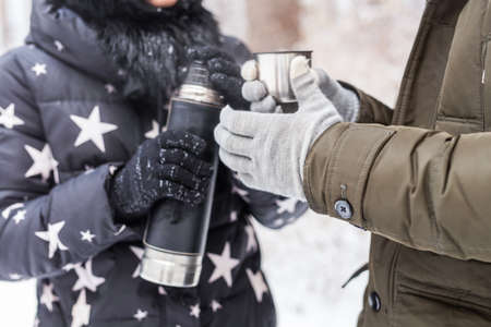 A woman pours a hot drink. Couple on a winter holidayの写真素材