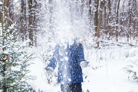 Cute young boy plays with snow, have fun, smiles. Teenager in winter park. Active lifestyle, winter...
