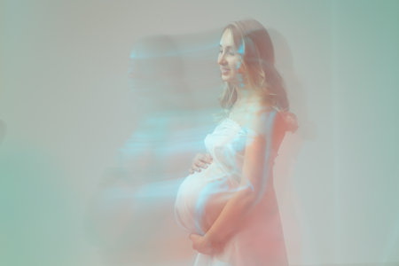 Elegant pregnant young woman standing wearing light fabric. Pregnancy, fantasy and fairy tale concept.の写真素材