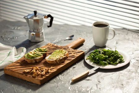 Sliced avocado on toast bread with nuts and coffee. Breakfast and healthy food concept.の写真素材