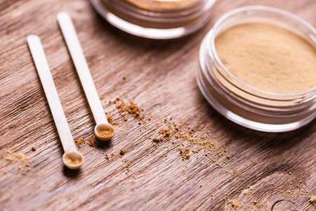Mineral powder of different colors with a spoon dispenser for make-up on wooden backgroundの写真素材