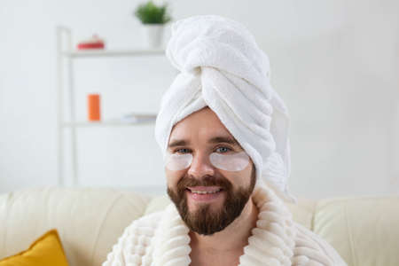 Bearded man sitting with eye patches on his face. Wrinkles and face home care for men.の写真素材