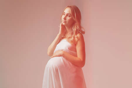 Elegant pregnant young woman standing wearing light fabric. Pregnancy, fantasy and fairy tale concept.の写真素材