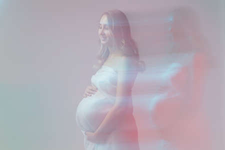 Elegant pregnant young woman standing wearing light fabric. Pregnancy, fantasy and fairy tale concept.の写真素材