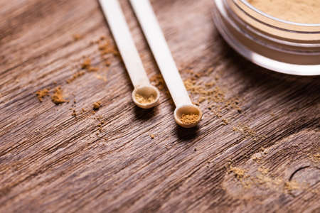 Mineral powder of different colors with a spoon dispenser for make-up on wooden background