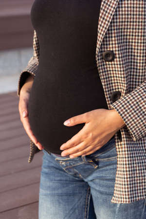Active pregnancy concept. Close-up of belly of happy young business or student pregnant woman...