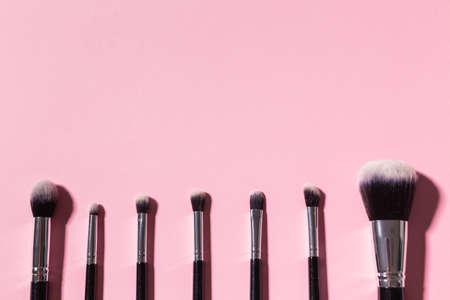 Various make-up brushes on pink background with copy space, top view. Cosmetics and beauty concept.の写真素材