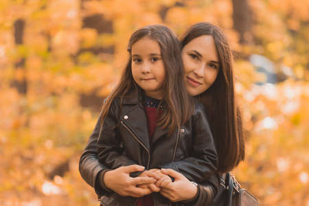 Little girl playing with mother in the autumn parkの写真素材