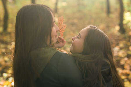 Little girl playing with mother in the autumn park