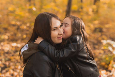 Little girl playing with mother in the autumn park