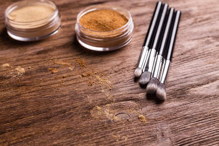 Loose compact mineral powder for face and a brushes for powder and visage on wooden background. Eco friendly and organic cosmetics.の写真素材