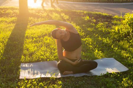 Pregnant woman doing fitness exercise on the grass in summer day. Healthy lifestyle.の写真素材