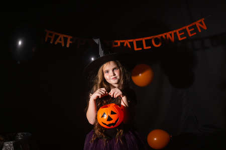 Funny child girl in witch costume for Halloween with pumpkin Jack.の写真素材