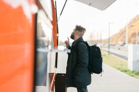 Portrait of man choosing fast food in food truck in the street. Meal, food industry and streetfood concept.の写真素材