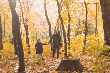 Mother and her little daughter in autumn park in fall season.の写真素材