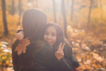 Mother and daughter spend time together in autumn yellow park. Season and single parent concept.の写真素材