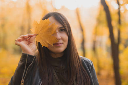 Portrait of autumn woman with fall leaf on nature background. Seasonal concept.の写真素材
