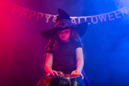 Little witch child cooking potion in the cauldron on Halloween.の写真素材