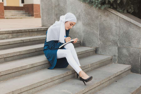 Arab female student sitting on stairs in downtown.の写真素材