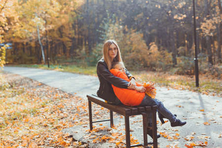 Single parent mother and child boy in the autumn in park sit on bench. Fall season and family...
