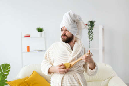 Funny handsome man pretends to play on massage brush as a guitar. Fun, spa and humor concept.の写真素材