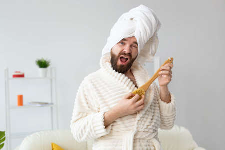 Funny handsome man pretends to play on massage brush as a guitar. Fun, spa and humor concept.の写真素材
