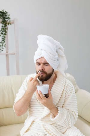Funny man applying effective cream on his facial skin. Spa at home, body and skin care for male concept.の写真素材