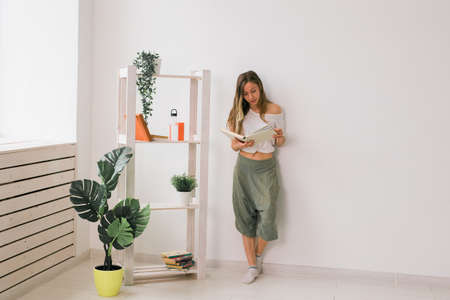 Young woman looking photo album at home. Memories and leisure concept.の写真素材