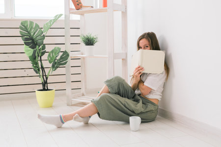 Girl covers her face with book. Literature, reading and knowledge concept.の写真素材