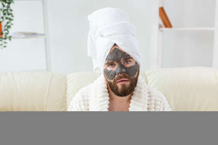 Bearded man has clean fresh skin, wears beauty clay mask on face and enjoys beauty treatments. Spa at home, body and skin careの写真素材