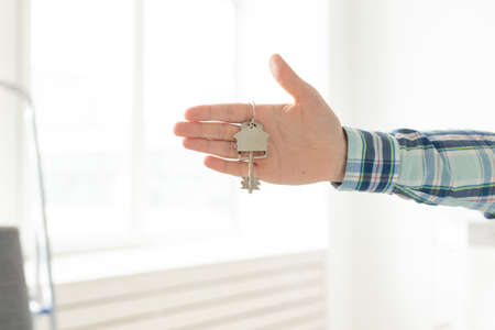 Holding house keys on house shaped keychain in a new home. Mortgage and home loan concept.の写真素材