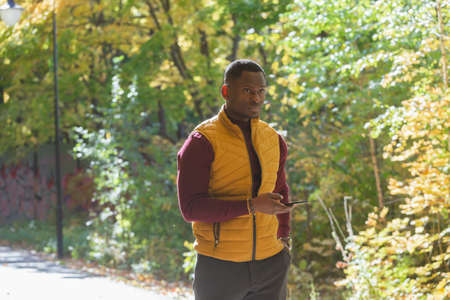 African american student walking in the park in autumn seasonの写真素材
